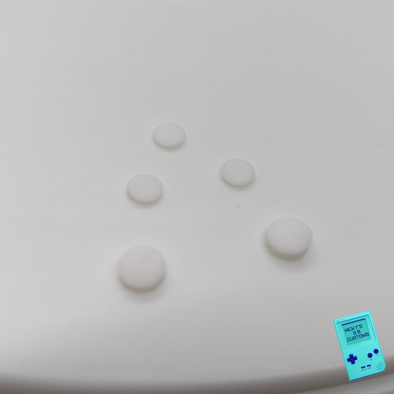 Peut inclure: Cinq boutons ronds blancs sur une surface blanche.
