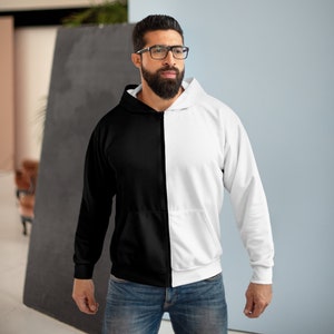 May include: A black and white zip-up hoodie with a contrasting colour split down the middle. The hoodie has a hood and long sleeves.