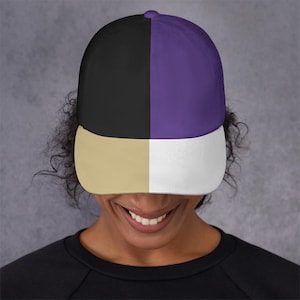 Peut inclure: Casquette de baseball avec un design en blocs de couleurs. Le chapeau est divisé en quatre sections : noir, violet, beige et blanc. Il a une couronne arrondie et une visière incurvée.
