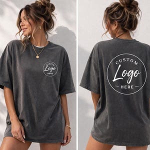 A woman wearing a gray t-shirt with the text "CUSTOM Logo HERE" printed on the back.