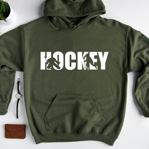 May include: A green hooded sweatshirt with the word "HOCKEY" printed in white. The word is formed by hockey players in silhouette.