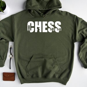 以下が含まれることがあります： チェスの駒が文字に組み込まれた「CHESS」という白いグラフィックが施された緑色のフード付きスウェットシャツです。