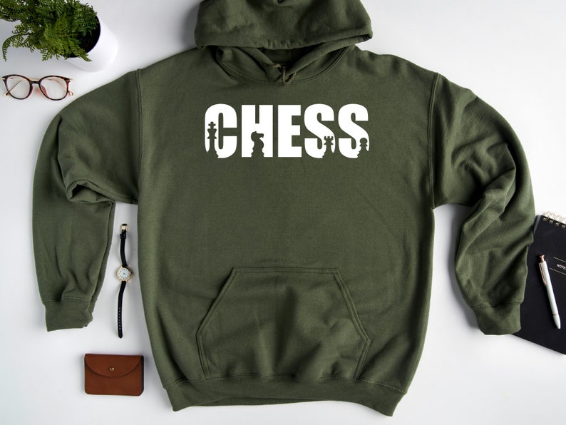 以下が含まれることがあります： チェスの駒が文字に組み込まれた「CHESS」という白いグラフィックが施された緑色のフード付きスウェットシャツです。