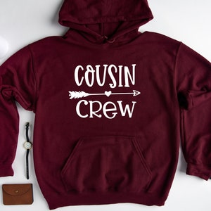 May include: Burgundy hooded sweatshirt with white text that reads "COUSIN CREW" with an arrow and a heart.