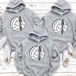 May include: Three gray hooded sweatshirts with a volleyball graphic and the name "Emily" printed vertically down the side of the volleyball.