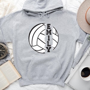 May include: Gray hooded sweatshirt with a white volleyball graphic and the name "EMILY" printed vertically down the side of the volleyball.