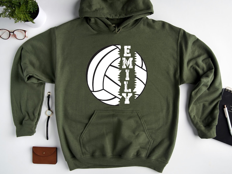 May include: A green hooded sweatshirt with a white volleyball graphic and the word "EMILY" printed vertically down the side of the volleyball.