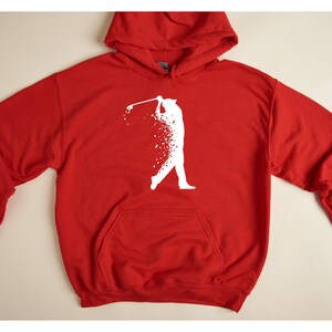 Op de afbeelding: Rood hoodie met een wit silhouet van een golfer die een club zwaait. De golfer is gemaakt van witte stippen.