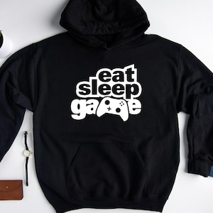 May include: Black hoodie with a white graphic that says "eat sleep game" with a video game controller icon.