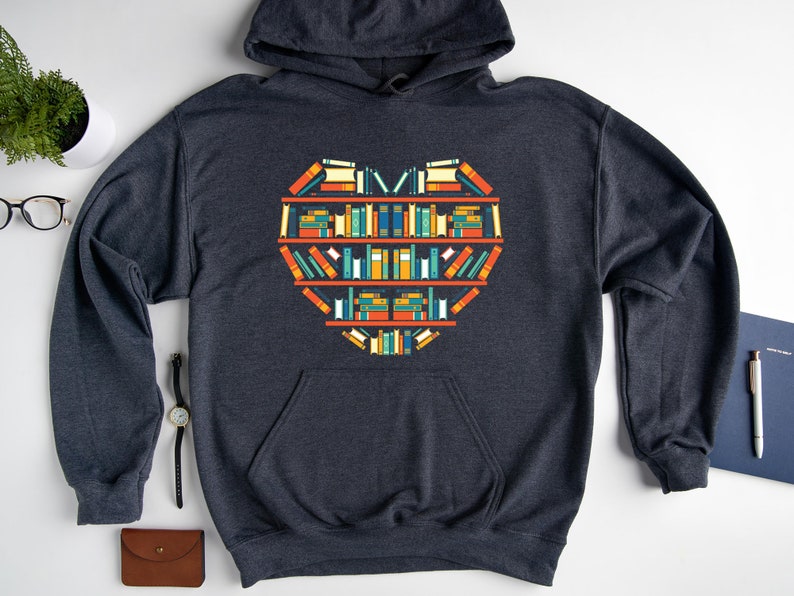 K&ouml;nnte beinhalten: Ein dunkelgrauer Kapuzenpullover mit einem grafischen Design eines herzf&ouml;rmigen B&uuml;cherregals, das mit bunten B&uuml;chern gef&uuml;llt ist.
