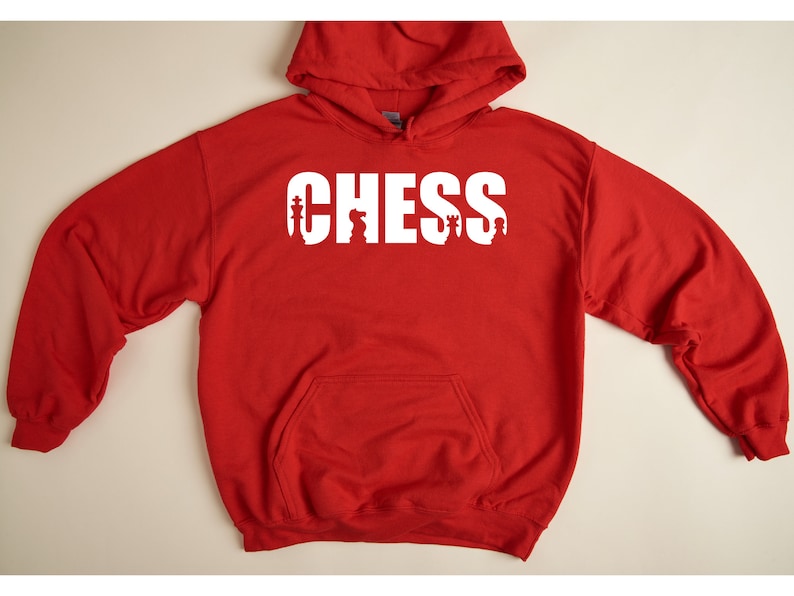以下が含まれることがあります： チェスの駒が文字に組み込まれた「CHESS」という白いグラフィックが施された赤いフード付きスウェットシャツです。