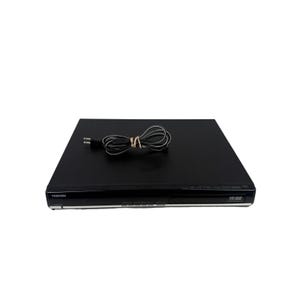 May include: A black Toshiba HD DVD player with a slim rectangular profile. The front panel features the Toshiba logo on the left and an HD DVD logo on the right. A black power cord with a two-prong plug is coiled on top of the device.