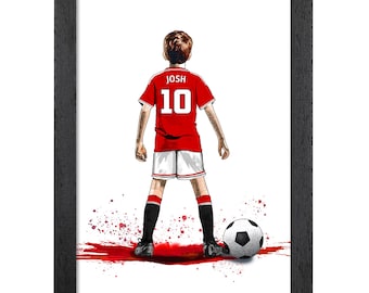 Può includere: Una stampa artistica incorniciata di un calciatore visto di spalle, che indossa una maglia rossa con il nome JOSH e il numero 10 in bianco, pantaloncini bianchi e calzettoni neri. Un pallone da calcio è ai piedi con schizzi di vernice rossa.