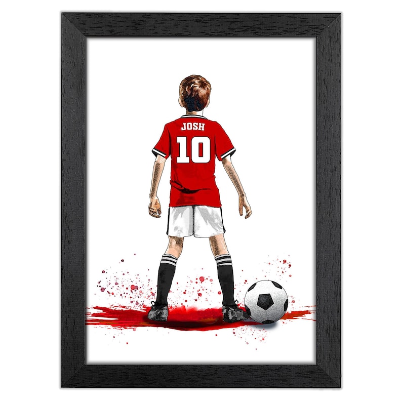 Puede incluir: Impresi&oacute;n art&iacute;stica enmarcada que presenta a un joven jugador de f&uacute;tbol con una camiseta roja con el nombre "JOSH" y el n&uacute;mero "10" en la espalda. El jugador est&aacute; frente a un bal&oacute;n de f&uacute;tbol. La obra es de estilo acuarela con salpicaduras de pintura roja.
