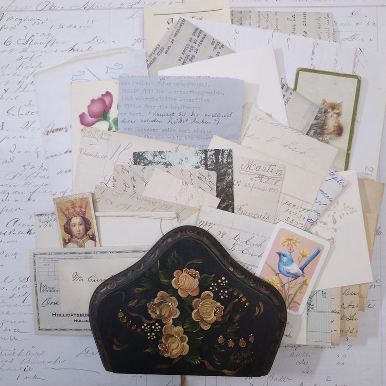 Pode incluir: Uma cole&ccedil;&atilde;o de efem&eacute;rides vintage, incluindo cartas manuscritas, postais e uma caixa preta decorativa com desenhos florais pintados. O sortido apresenta uma variedade de texturas e cores de papel, criando uma est&eacute;tica nost&aacute;lgica.