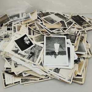 Puede incluir: Un gran montón desordenado de fotografías antiguas en blanco y negro de varios tamaños. La colección presenta instantáneas espontáneas, retratos y escenas al aire libre, con algunas imágenes que muestran notas escritas a mano en el reverso.