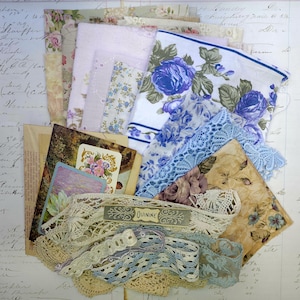 May include: A collection of vintage ephemera including floral handkerchiefs, lace trim, playing cards, and patterned fabric scraps. The color palette includes shades of blue, pink, cream, and tan. A label reads "QUININE".
