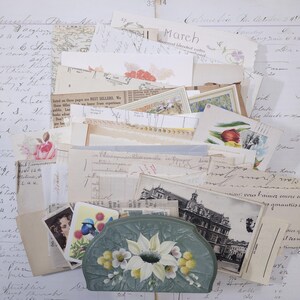 Pode incluir: Uma cole&ccedil;&atilde;o de ef&ecirc;meras vintage, incluindo postais, cartas manuscritas e ilustra&ccedil;&otilde;es florais. Uma clutch verde pintada &agrave; m&atilde;o com flores brancas e amarelas est&aacute; entre os pap&eacute;is. A palavra "March" &eacute; vis&iacute;vel.