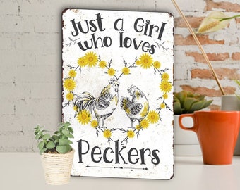 May include: A white metal sign with a rustic look featuring a heart made of yellow sunflowers with two chickens inside. The sign reads "Just a Girl who loves Peckers".