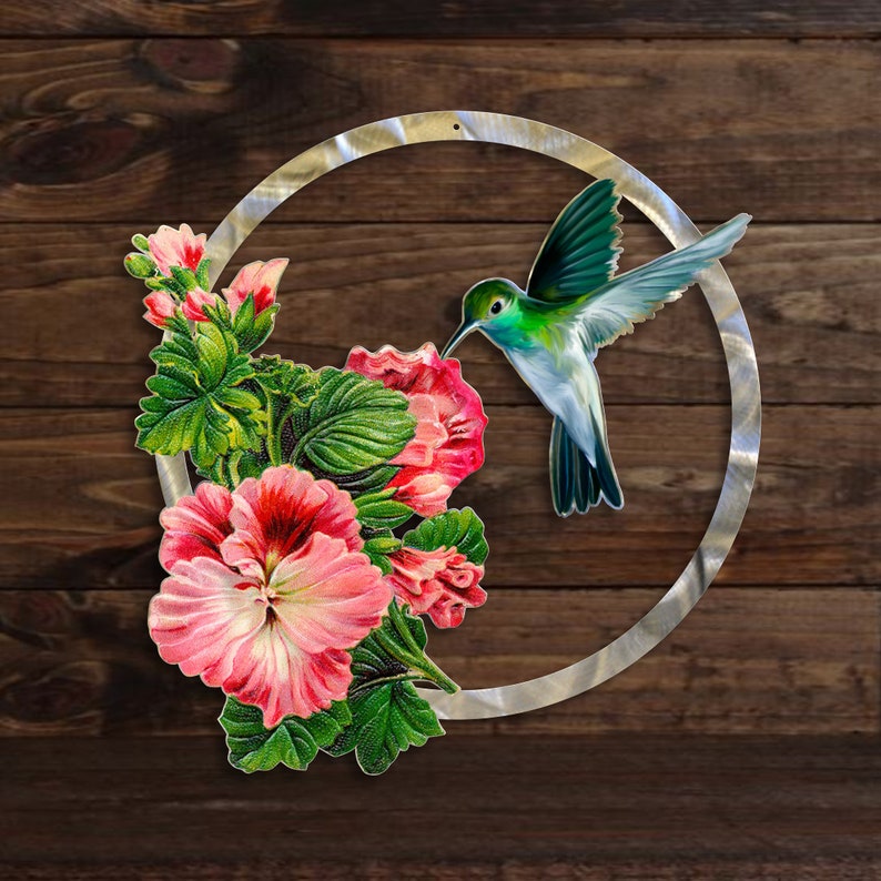 May include: A metal circle with a hummingbird and pink flowers. The hummingbird is green, blue, and white. The flowers are pink with green leaves.