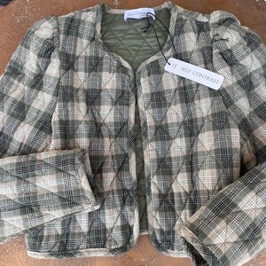 May include: A green and white checked quilted jacket with a self contrast label. The jacket has a slightly puffed sleeve and a cropped length.