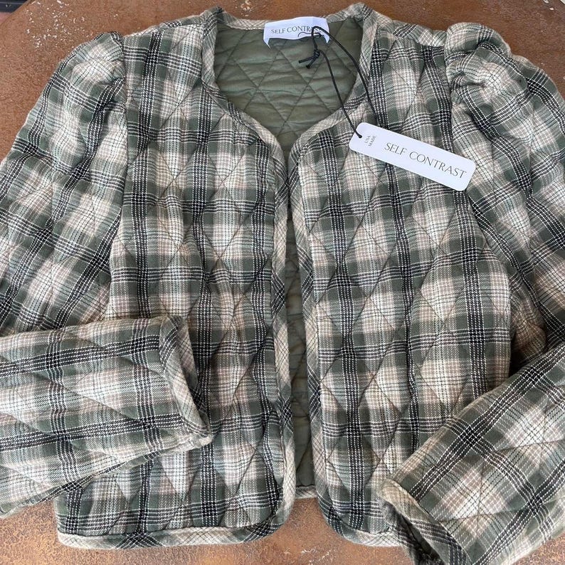 May include: A green and white checked quilted jacket with a self contrast label. The jacket has a slightly puffed sleeve and a cropped length.