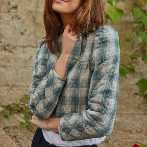 May include: A green and white checked quilted jacket with a high neck and puff sleeves.