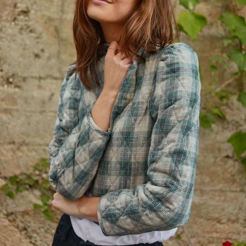 May include: A green and white checked quilted jacket with a high neck and puff sleeves.
