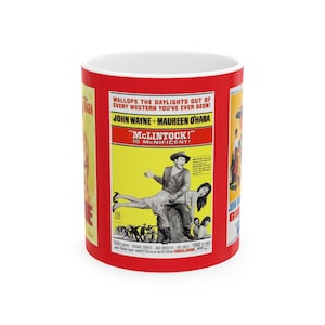 May include: A red ceramic mug with a vintage movie poster design featuring John Wayne and Maureen O'Hara in the film "McLintock!" The poster text reads "Wallops the daylights out of every western you've ever seen!" and "McLintock! Is menificent!"