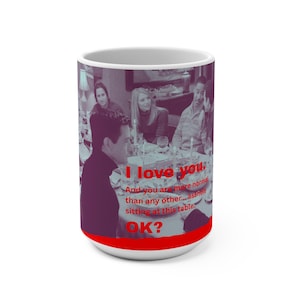 May include: White ceramic mug with a red base and rim. The mug features a photo of a group of people at a table, with the text "I love you. And you are more normal than any other... asshole sitting at this table. OK?"