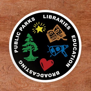 Puede incluir: Una pegatina circular negra con el texto blanco PUBLIC PARKS LIBRARIES EDUCATION BROADCASTING alrededor del borde. El centro contiene una estrella amarilla, un libro abierto naranja, un megáfono azul, un árbol verde y un corazón rojo.