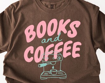 May include: A brown short-sleeve t-shirt featuring the text "BOOKS and COFFEE" in large pink and teal lettering. Below the text is a simple teal line-art illustration of an espresso machine with a small cup placed underneath the spout.