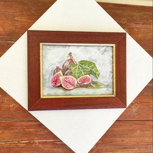 K&ouml;nnte beinhalten: Ein gerahmtes Gem&auml;lde eines Stilllebens mit einer Gruppe reifer Feigen mit gr&uuml;nen Bl&auml;ttern. Die Feigen sind tiefviolett und einige sind aufgeschnitten, um ihr rosa Fruchtfleisch zu zeigen. Das Gem&auml;lde ist vor einem hellblauen Hintergrund gemalt.