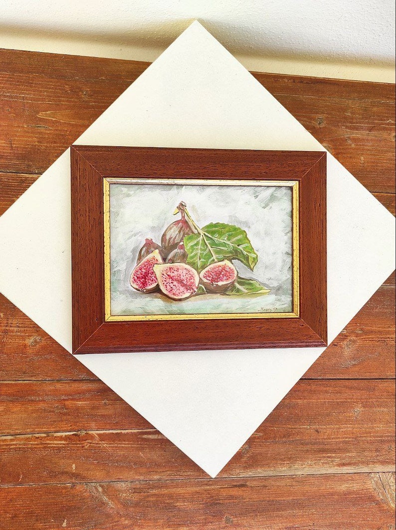 K&ouml;nnte beinhalten: Ein gerahmtes Gem&auml;lde eines Stilllebens mit einer Gruppe reifer Feigen mit gr&uuml;nen Bl&auml;ttern. Die Feigen sind tiefviolett und einige sind aufgeschnitten, um ihr rosa Fruchtfleisch zu zeigen. Das Gem&auml;lde ist vor einem hellblauen Hintergrund gemalt.