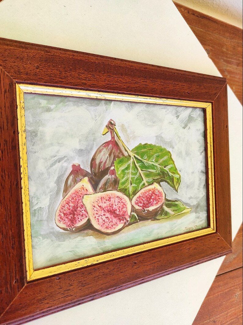 K&ouml;nnte beinhalten: Ein gerahmtes Gem&auml;lde mit einem Stillleben aus Feigen und einem Blatt. Die Feigen sind in Schattierungen von Lila, Rosa und Gr&uuml;n gemalt. Das Blatt ist dunkelgr&uuml;n. Das Gem&auml;lde ist in einem dunklen Holzrahmen mit goldener Verzierung gerahmt.