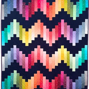 May include: A vibrant quilt with a dark blue backdrop and a zig-zag design in rainbow shades. The quilt showcases a spectrum of colours, such as pink, orange, yellow, green, and blue, forming an eye-catching pattern. This quilt is a comfortable and decorative home textile.