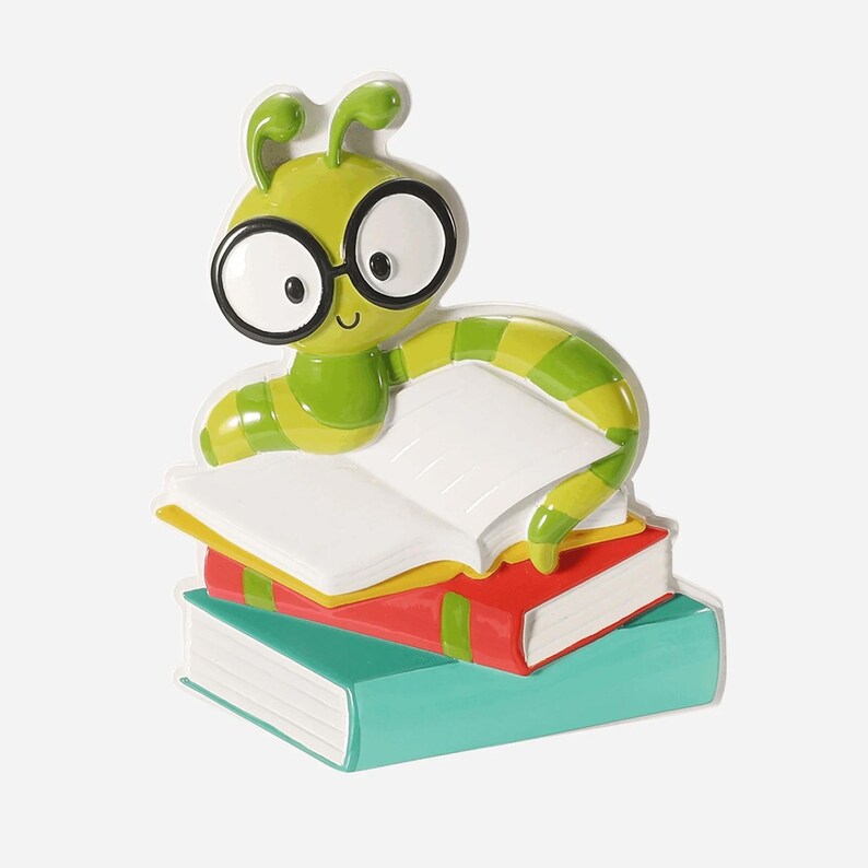 Op de afbeelding: Een groene en gele cartoonrups met een bril, bovenop een stapel van drie kleurrijke boeken. De rups leest een open boek met witte pagina's. De boeken zijn rood, geel en turquoise.