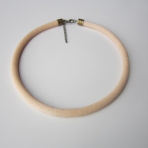 Op de afbeelding: Een delicate cr&egrave;mekleurige kralenketting met een eenvoudige metalen sluiting.