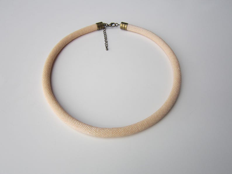 Op de afbeelding: Een delicate cr&egrave;mekleurige kralenketting met een eenvoudige metalen sluiting.