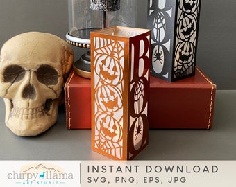 May include: Two black and orange paper lantern style decorations with the word "BOO" and a spider web design. The lanterns are on a brown surface with a skull in the background.