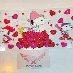 May include: A pink, white, and red Valentine's Day themed sticker sheet featuring Snoopy and Woodstock. The sheet includes hearts, stars, and the text "22 Pimee Stage".