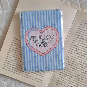 May include: A Kindle case featuring a light blue and white striped design with bows. It has a pink heart with the text "WHERE I GO MY KINDLE GOES".