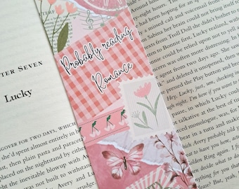 May include: A rectangular paper bookmark featuring a pink collage design with a clock, flowers, a butterfly, and a ticket stub labelled Love City Admit One $5. The text Probably reading Romance is printed in a white script font across the centre.