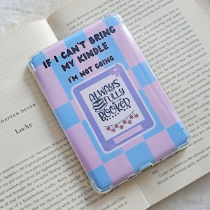 May include: A pink and blue checkered phone case with a clear plastic cover. The case has a sticker on it that says "If I can't bring my kindle I'm not going." The sticker also has a smaller sticker on it that says "Always fully booked" with a stack of books and hearts.