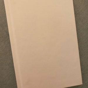 Op de afbeelding: Een blanco, wit, gebonden boek met een gladde, matte afwerking.