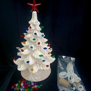 May include: A white ceramic Christmas tree with colorful lights and a red star topper. Includes a bag of replacement lights and a power cord. The tree is approximately 12 inches tall.