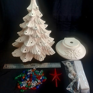May include: A ceramic Christmas tree with a base, a star topper, and a string of colorful lights. The tree is off-white with holes for lights. A ruler is next to the tree. The tree is approximately 12 inches tall.