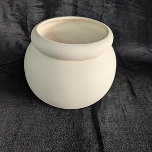 May include: A round, off-white ceramic pot with a wide, rounded rim. The pot has a smooth, matte finish and a simple, elegant design. The interior is a lighter shade of off-white. Ideal for plants or decorative use.