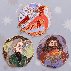 May include: Three enamel pins featuring characters from a fantasy series. The top pin depicts a wizard and a phoenix in red, gold, and blue. The other pins show a woman with a cat and a bearded man with a dragon, all with gold borders.