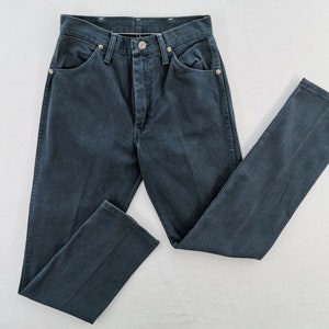 K&ouml;nnte beinhalten: Dunkelblaue Jeans mit klassischem F&uuml;nf-Taschen-Design. Die Jeans hat einen Knopf- und Rei&szlig;verschluss sowie silberne Nieten. Die Hose liegt flach auf einer wei&szlig;en Oberfl&auml;che.